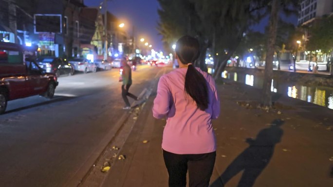 一名女子在夜间拥挤的城市街道上慢跑