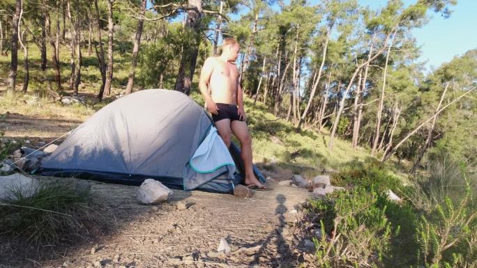 在土耳其费特希耶的露营地，一名露营者从帐篷里出来，一边伸懒腰，一边打哈欠。
