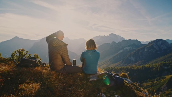 SLO MO山顶宁静:背包客在阿尔卑斯山的辉煌中休息，他们尽情享受周围山峰和山谷的全景