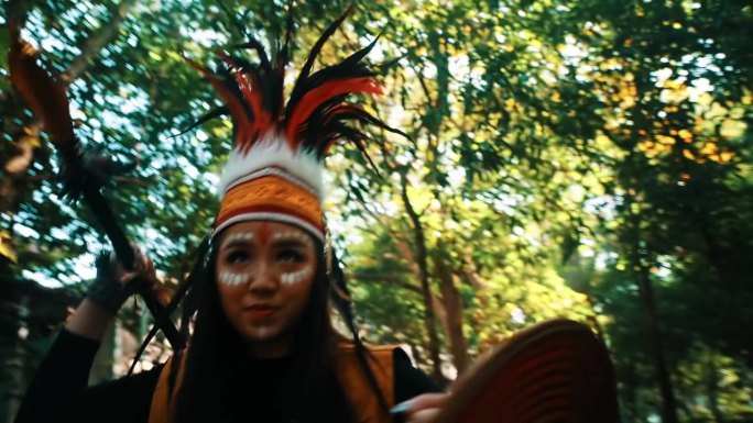 穿着传统服装、头戴羽毛头饰的土著妇女手持织成的扇子在森林中。