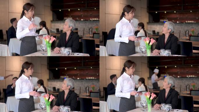 现代待客之道:亚洲见习女服务员接受顾客的数字平板订单