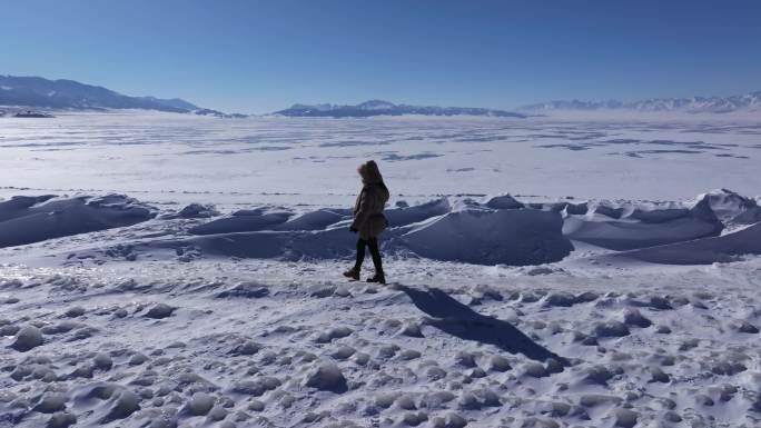 女孩在新疆赛里木湖白雪覆盖的湖面上行走
