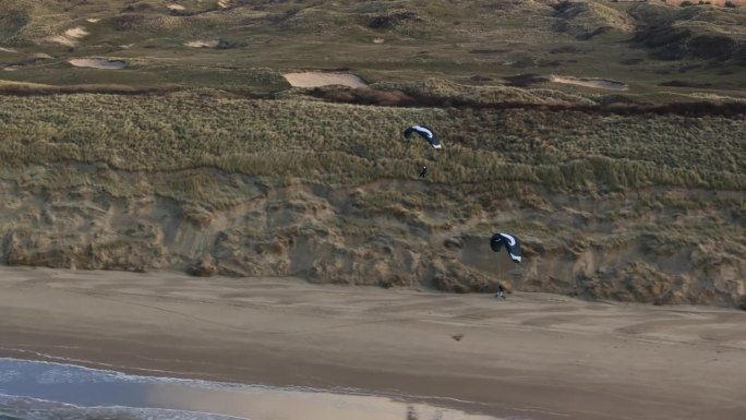 无人机拍摄的一对滑翔伞在荷兰Wijk Aan Zee的沙滩上翱翔