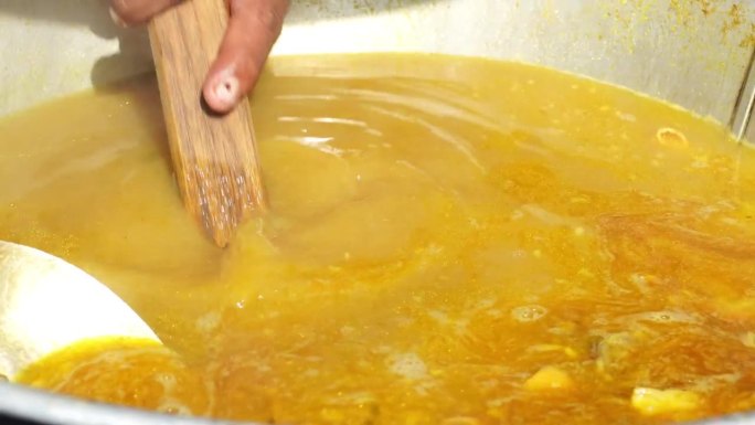 一个索托破损或牛肉索托摊贩用手搅拌装满内脏的索托肉汤的大锅。