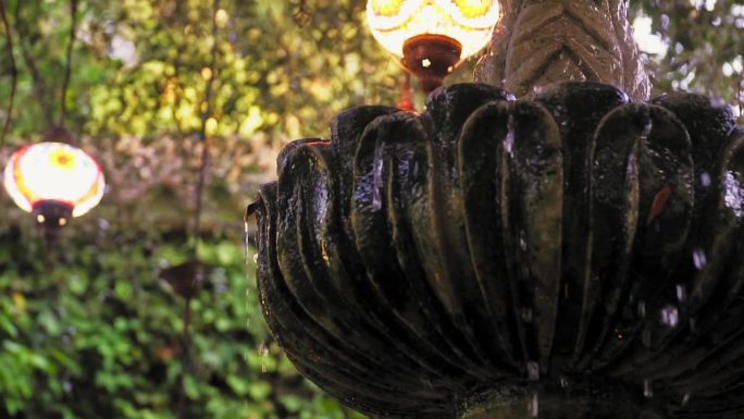 美丽的喷泉漏水与美丽的背景灯在室外花园周围。