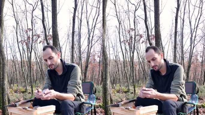木匠检查了一下雕刻刀的锋利程度，开始磨它。他坐在森林里的露营椅上。