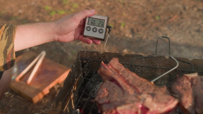 在野外露营时，用温度计近距离烤架烤牛排