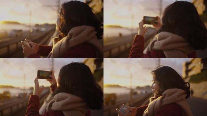 在夕阳的余晖中，年轻女子在沿海的铁路上拍照。