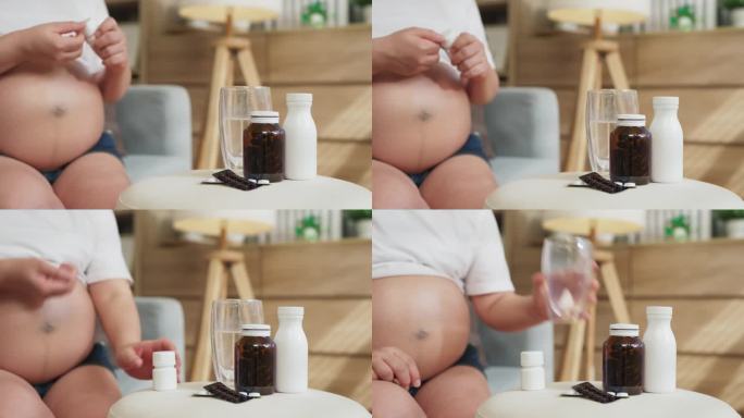 健康的生活方式怀孕的亚洲女性在家里的客厅里服用维生素和食物补充剂照顾她的新生儿。孕妇吃药