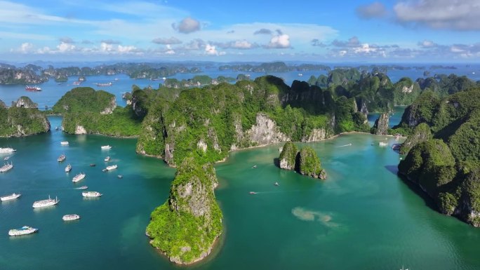 在越南北部下龙湾的海上，航拍无人机拍摄的观光船与岩石山的淡蓝色天空