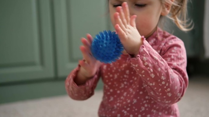可爱的女婴在玩有触觉的球形球。幼儿手玩感官按摩球。增强认知、生理过程。大脑发育。支持患有多动症、自闭
