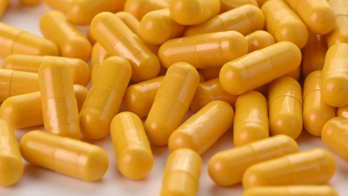 黄色药丸胶囊隔离在白色背景的特写。