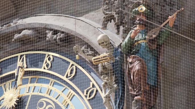 在中世纪建筑的钟旁演奏小提琴的蓝色雕像