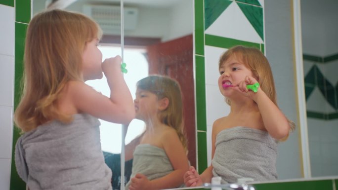 可爱的小女孩刷牙她的牙刷看着镜子。儿童日常保健例行程序。特写镜头
