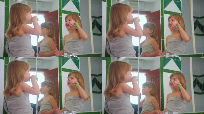 可爱的小女孩刷牙她的牙刷看着镜子。儿童日常保健例行程序。特写镜头
