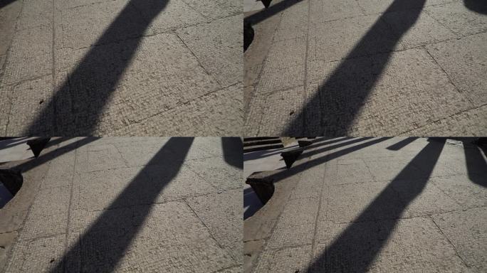 在晴朗的天空下，长长的影子投在突尼斯杜加的古罗马马赛克地板上