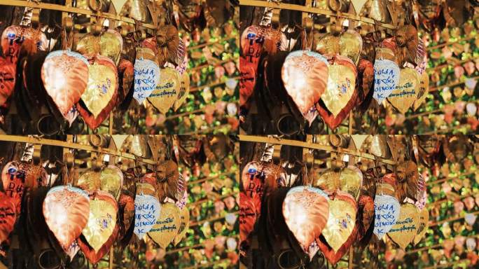 在曼谷沙吉寺的钟上悬挂着心形的金叶，上面写着信息和祝福