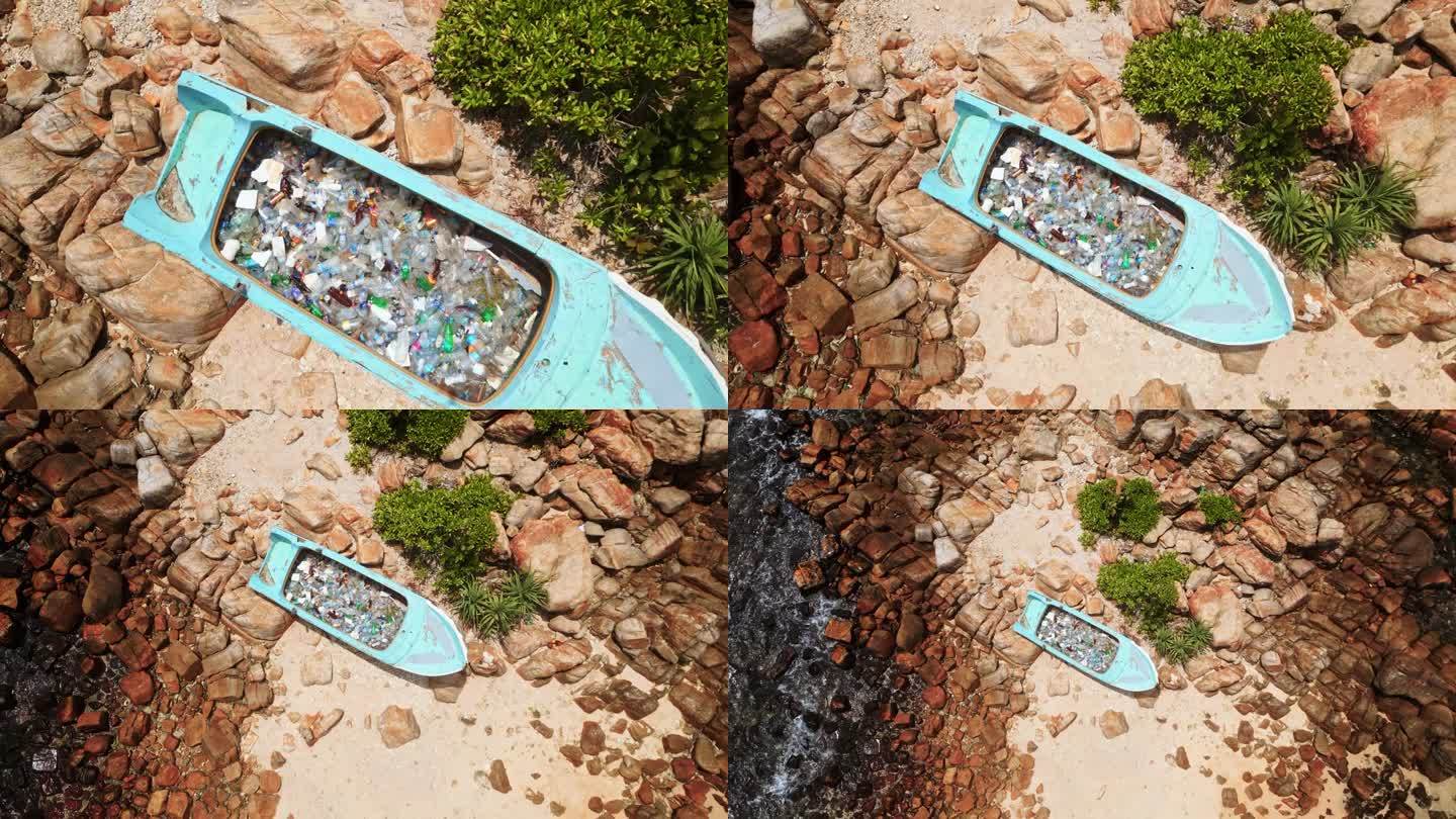 鸟瞰图:装满塑料瓶的废弃船只，岩石环绕的沙滩上的垃圾，提醒人们海洋污染。人们看得见，装满垃圾的船只凸