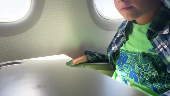坐飞机旅行的白人男孩在平板电脑上看视频