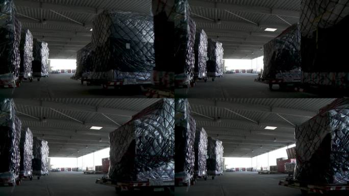 黑暗的仓库内部有一排排用黑色塑料包裹的托盘，可能用于存储或运输概念