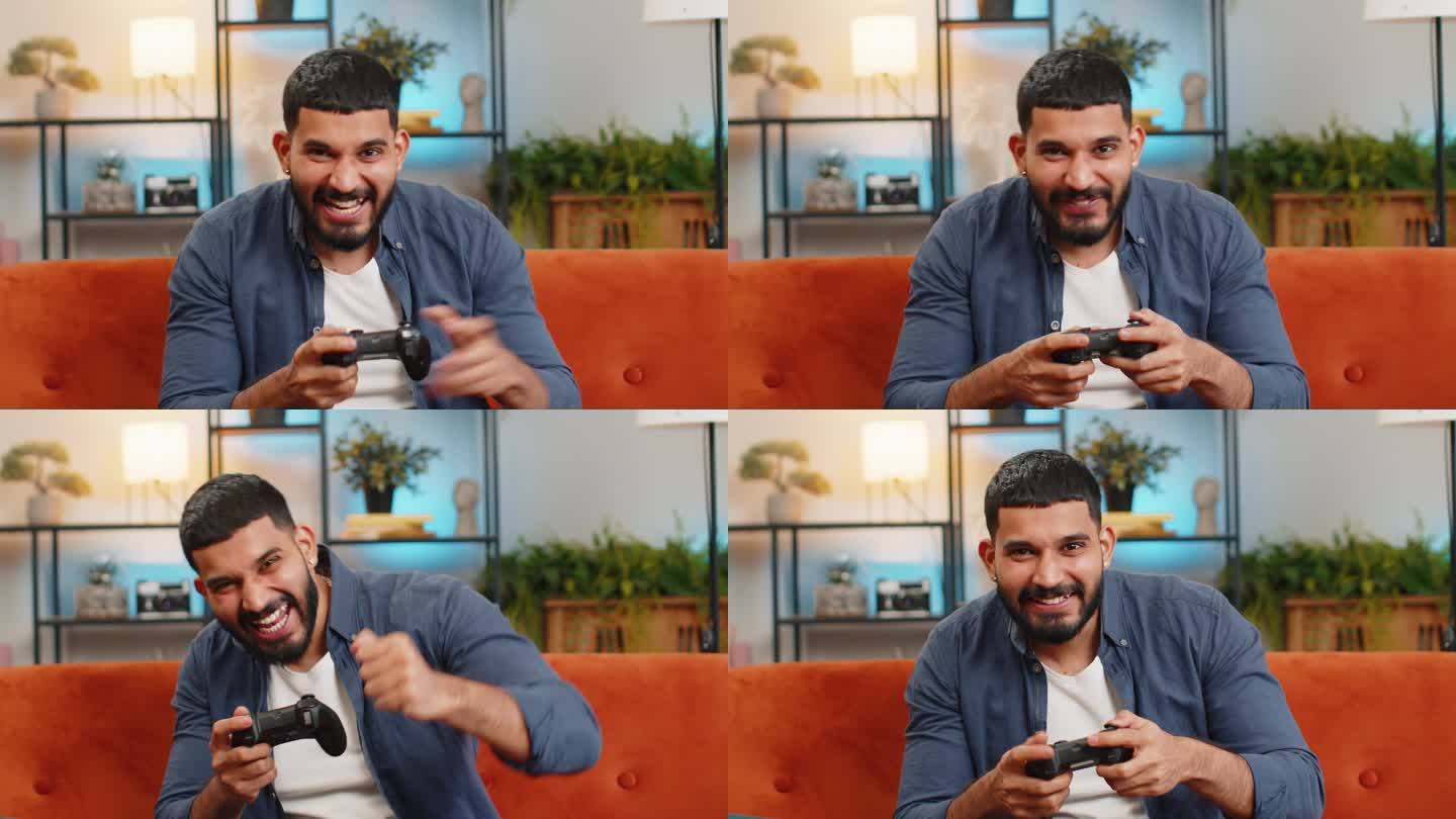 一名印度男子坐在家里的沙发上，用摇杆控制器玩视频游戏机，赢得了在线游戏的胜利