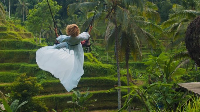 美丽的女人在巴厘岛的tegalalang梯田荡秋千。