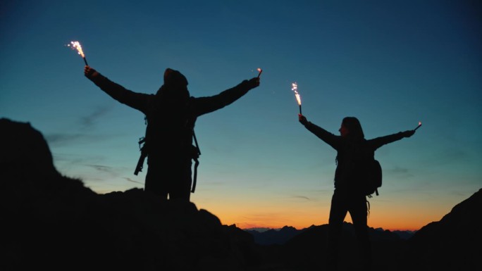 SLO MO暮光庆典:一对夫妇在山顶上用烟花点燃魔法。蓝色的小时。