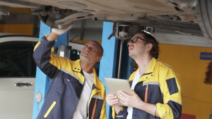 汽车修理店的两个机械师正在讨论如何修理一辆旧车的底盘和悬挂系统