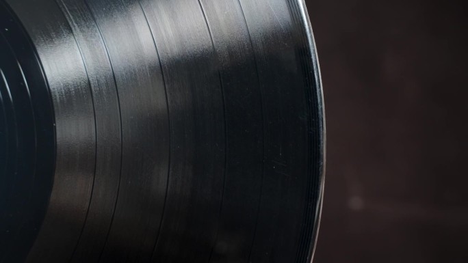 黑胶唱片在黑色背景上的特写。它旋转，露出它的质地。