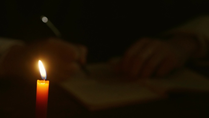 男人在蜡烛前学习笔记书写