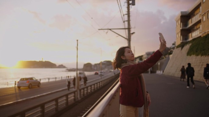 年轻女子在海上享受风在夕阳下。