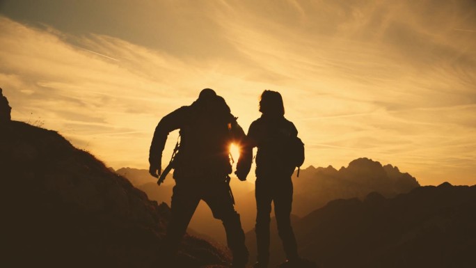 SLO MO拥抱高峰:一对夫妇在日落时分的山间小径上表达衷心支持的剪影
