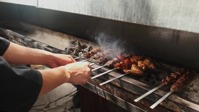 烤串师傅正在把烤架上煎好的鸡肉、肉、肝和蔬菜串起来