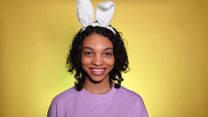 复活节摄影棚里可爱的女孩戴着兔子耳朵在眨眼。广告和促销理念