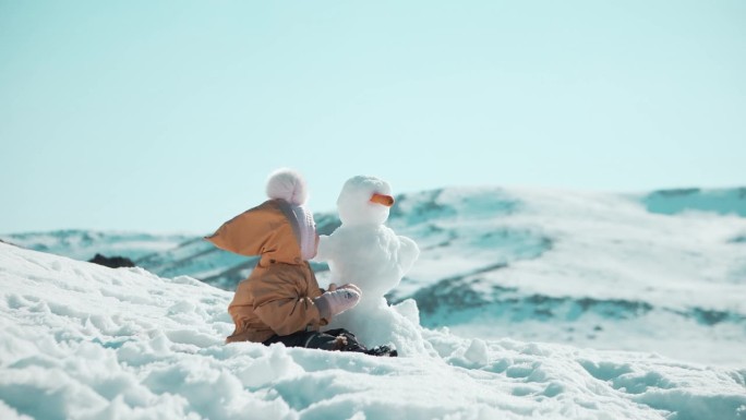 冬天，宝宝在山上的雪人旁边微笑