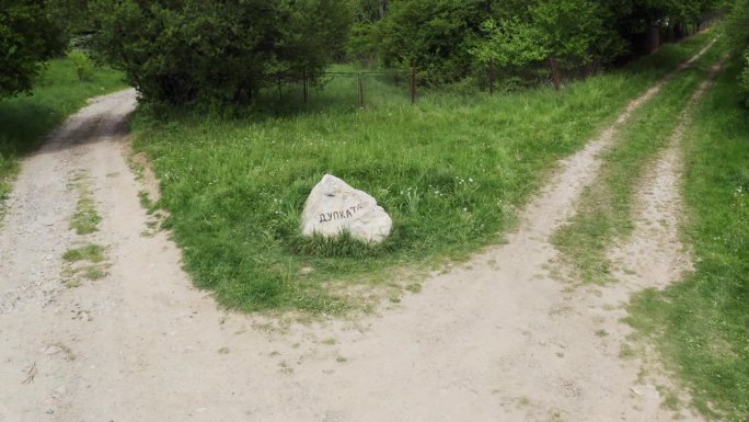 在保加利亚Tsarichina Hole村一个树木繁茂的地区，无人机在十字路口中间的天然岩石地标上从