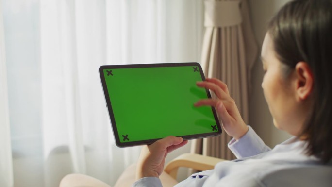 不认识的女人在家里用她的绿屏平板电脑