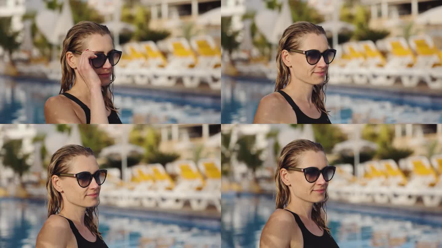 头发湿漉漉、戴着墨镜的女子在度假胜地的游泳池边放松