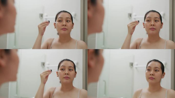 亚洲年轻女子在脸上涂抹精华液