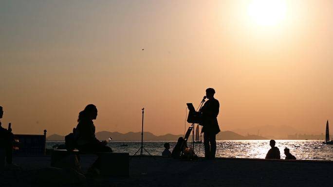 夕阳下剪影海边弹吉他唱歌演奏表演流浪歌手