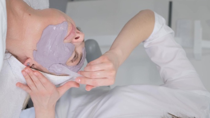 美容师用抹刀在脸上涂上海藻酸盐面膜。化妆品果冻面膜，面部皮肤护理。