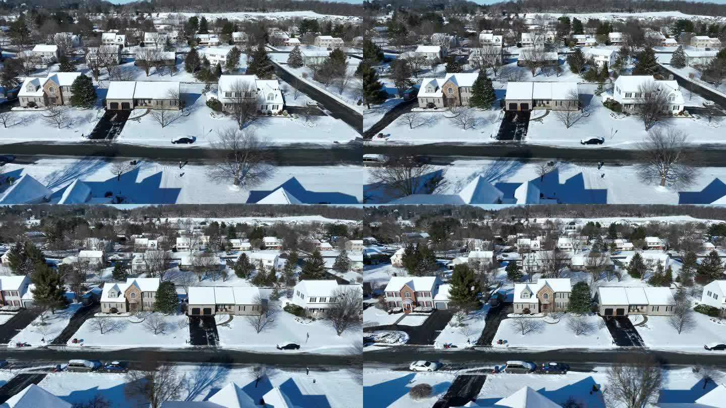 航拍全景照片显示美国郊区的一个白雪皑皑的村庄。阳光明媚的一天，街道上融化的雪。背景是森林景观。广角镜