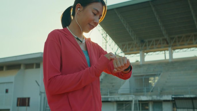 年轻的亚洲女运动员跑步者在户外跑步前检查智能手表的进度和看智能手表心率监测器。健康的锻炼。