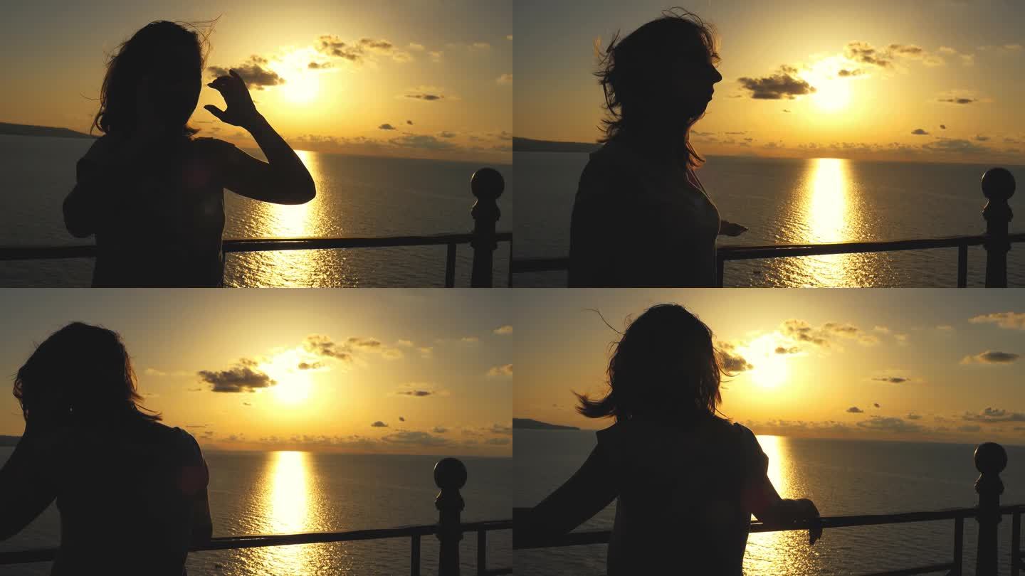 女人在欣赏海上金色的日落时，把头发在风中拂过