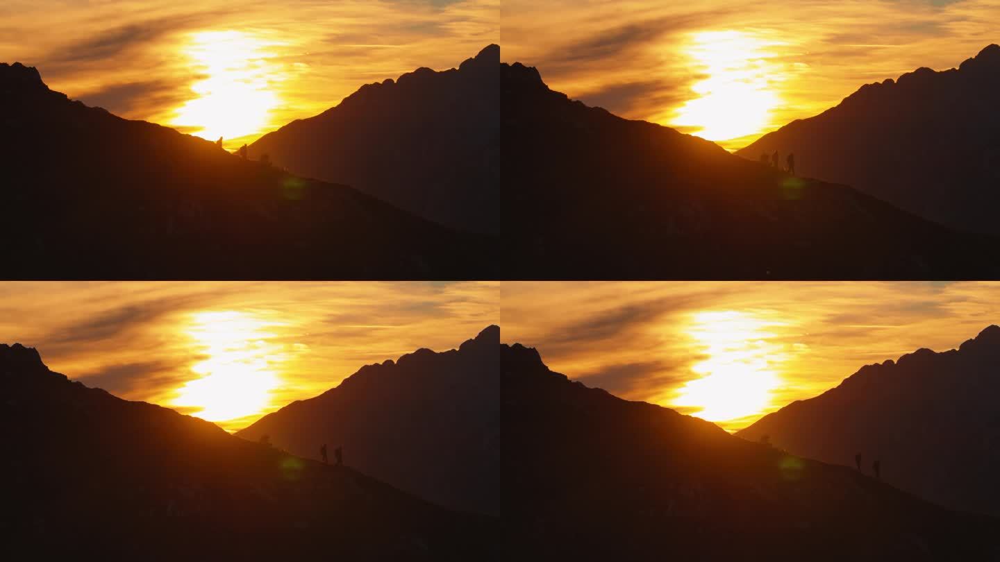 黄昏下降:两个徒步旅行者在山脊上下降的剪影