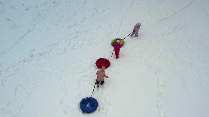 三胞胎小姐妹在冬天拿着充气芝士蛋糕爬雪山