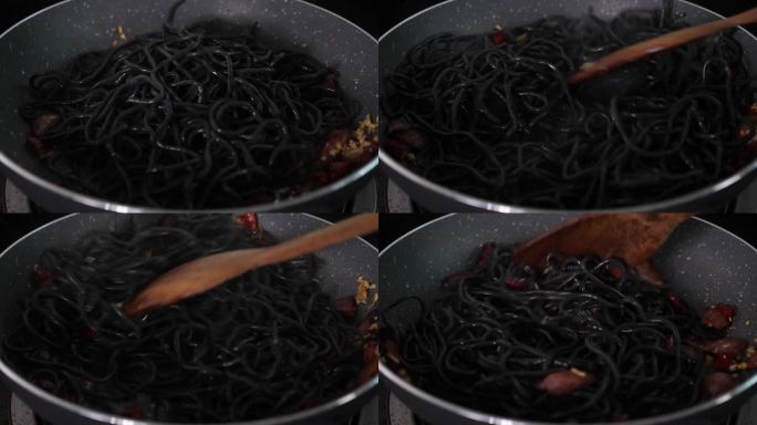 在餐厅或家中用墨汁做意大利面，黑色背景上的热煎锅上升起了慢动作的白烟。
