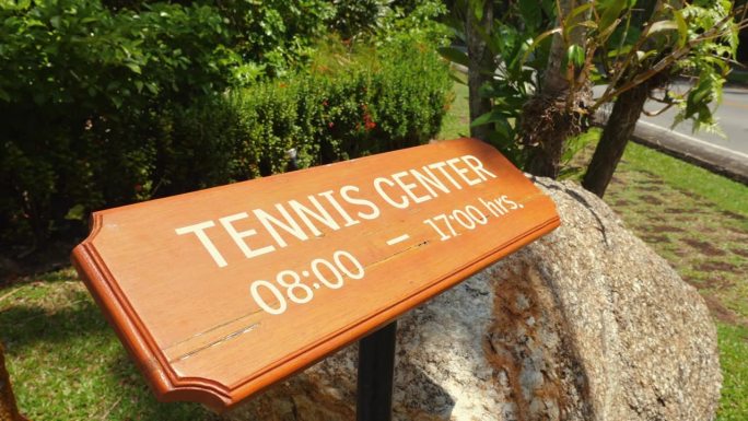 网球中心的信息牌显示在木板上，注明营业时间