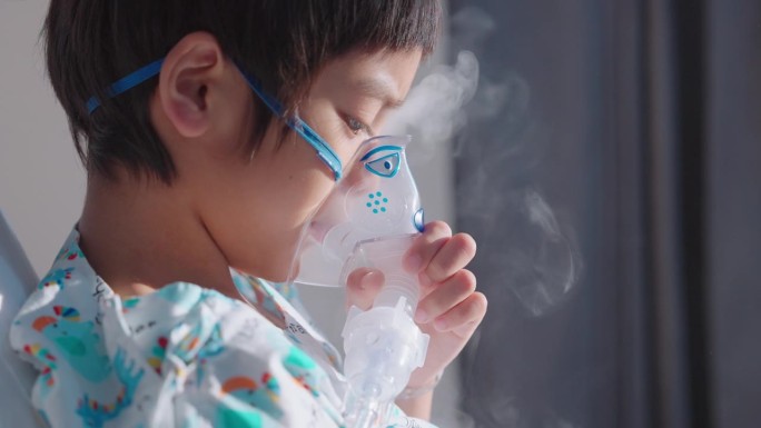 患病的亚洲男孩用吸入器呼吸，肺炎在医院康复