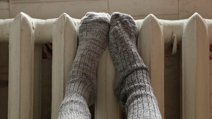 穿着袜子的脚放在公寓里的铸铁散热器上，没有暖气